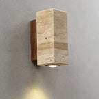 Square stone wall sconce with a walnut-tone back plate casting light down a grey wall