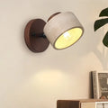 Stone wall light on a walnut-tone round mount, lit, beside a shelf