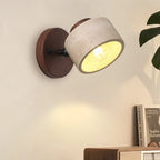 Stone wall light on a walnut-tone round mount, lit, beside a shelf
