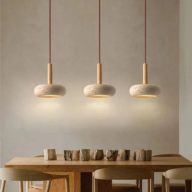 Row of three stone disc pendant lights over a wooden dining table