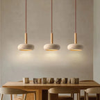 Row of three stone disc pendant lights over a wooden dining table