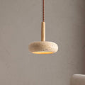 Stone disc pendant light on a wood stem hanging against a plaster wall