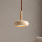 Stone disc pendant light on a wood stem hanging against a plaster wall