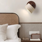 Stone wall light on a walnut-tone mount above a bed with a rattan headboard