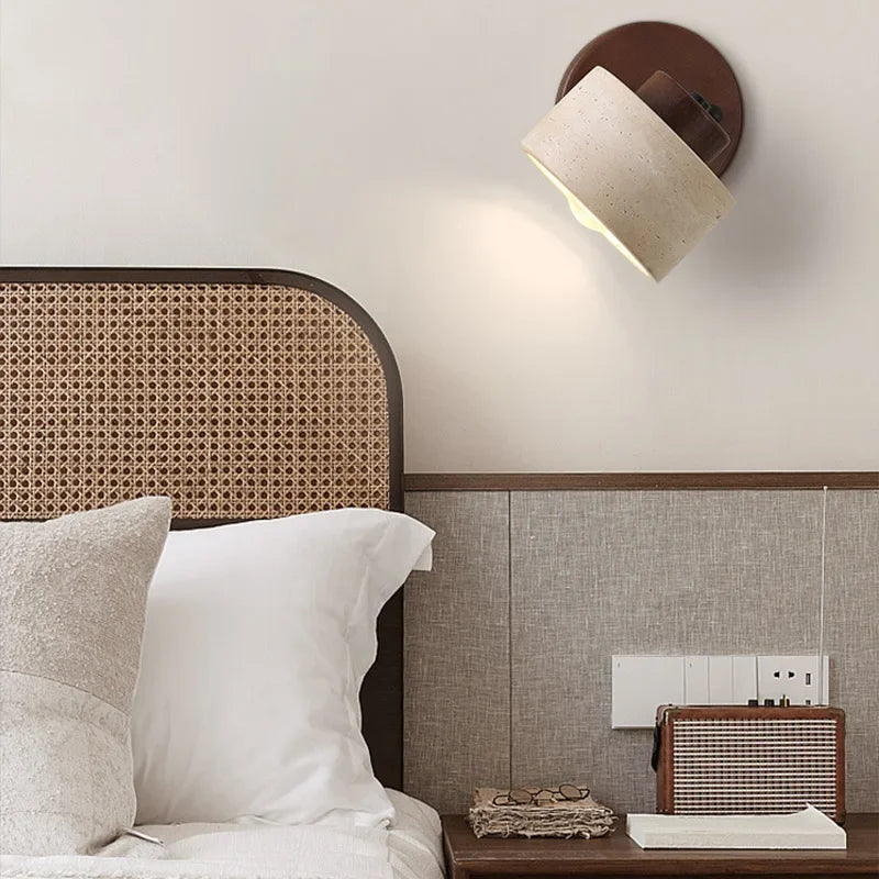 Stone wall light on a walnut-tone mount above a bed with a rattan headboard