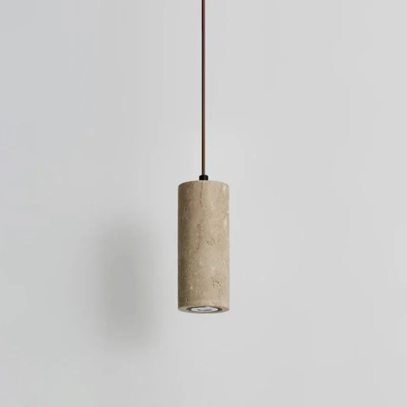 Slim marble cylinder pendant light hanging against a pale wall