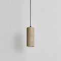 Slim marble cylinder pendant light hanging against a pale wall