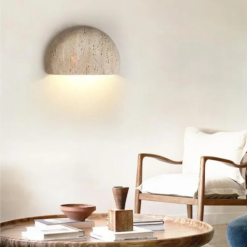 Half-dome stone wall light above a round coffee table and wooden chair