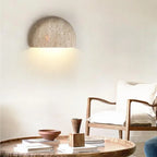 Half-dome stone wall light above a round coffee table and wooden chair
