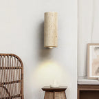 Round stone wall sconce beside a rattan chair and bedside table