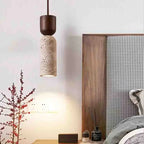 Stone-look pendant light hung beside a wooden headboard