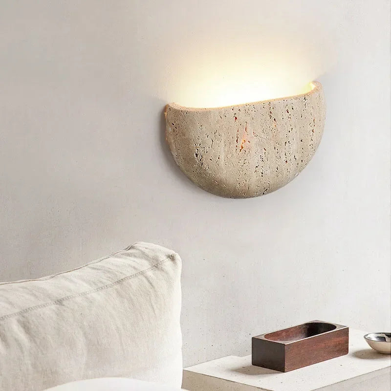 Half-dome stone wall light above a low shelf and a cream sofa