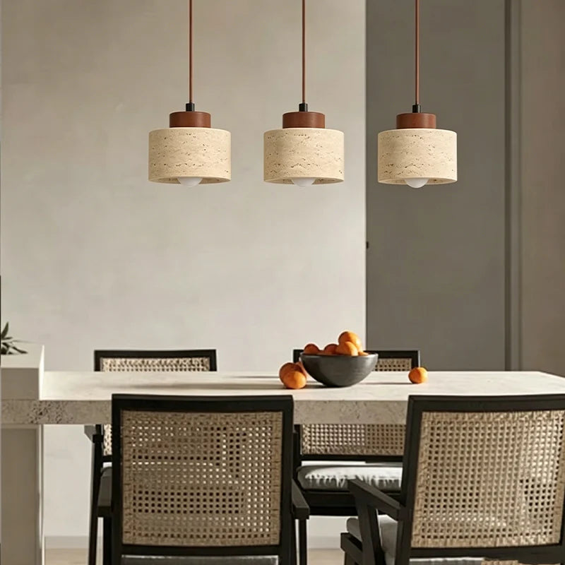Three small stone pendant lights with wood caps hanging over a dining table