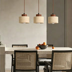 Three small stone pendant lights with wood caps hanging over a dining table