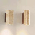 Two stone wall sconces, round and square, on a warm wall with walnut-tone back plates