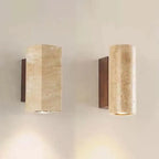 Two stone wall sconces, round and square, on a warm wall with walnut-tone back plates