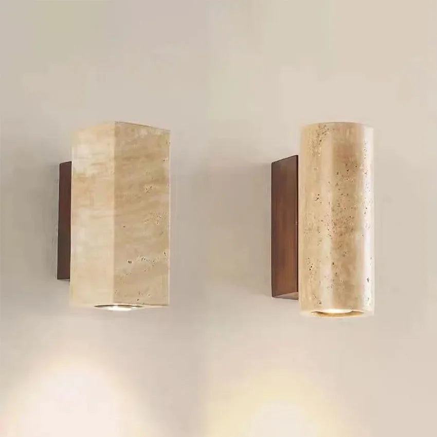 Two stone wall sconces, round and square, on a warm wall with walnut-tone back plates