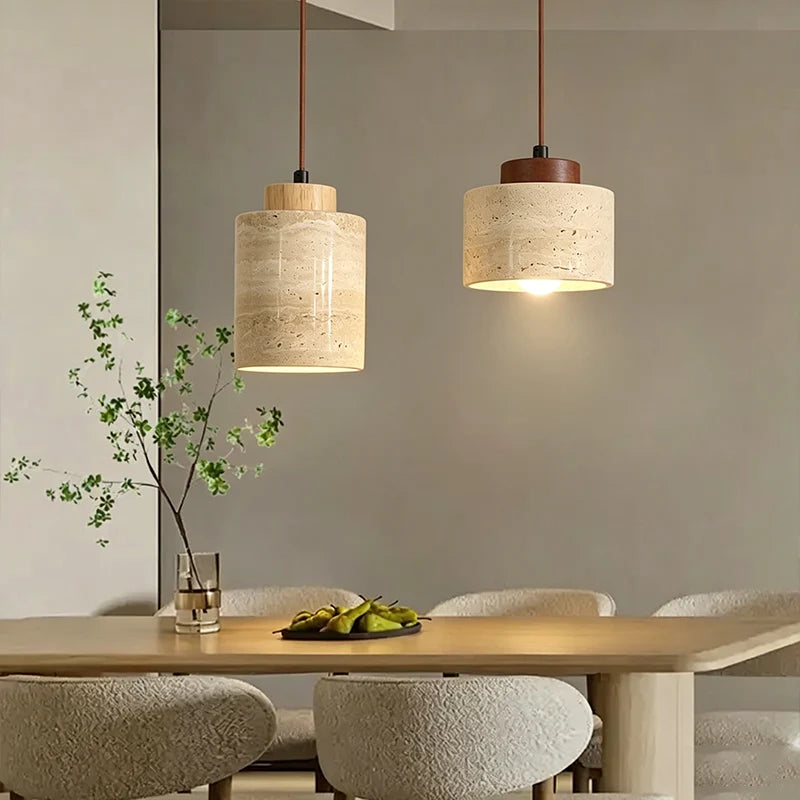 Two stone cylinder pendant lights with wood caps glowing above a set table
