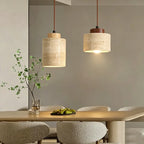Two stone cylinder pendant lights with wood caps glowing above a set table