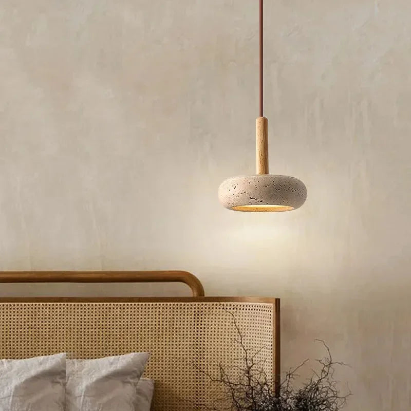 Stone disc pendant light beside a rattan bed headboard