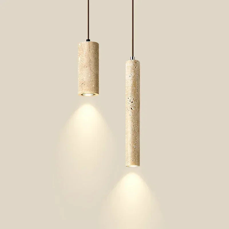 Two marble cylinder pendant lights of different widths glowing against a cream wall