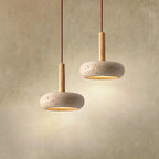 Two stone disc pendant lights at different heights glowing on a warm wall