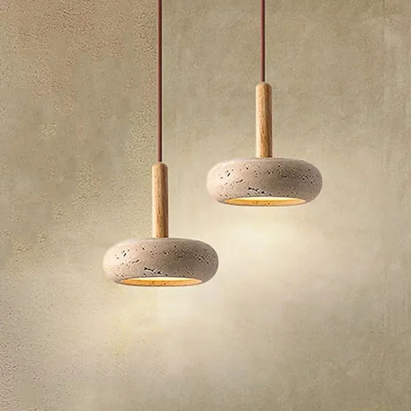 Two stone disc pendant lights at different heights glowing on a warm wall