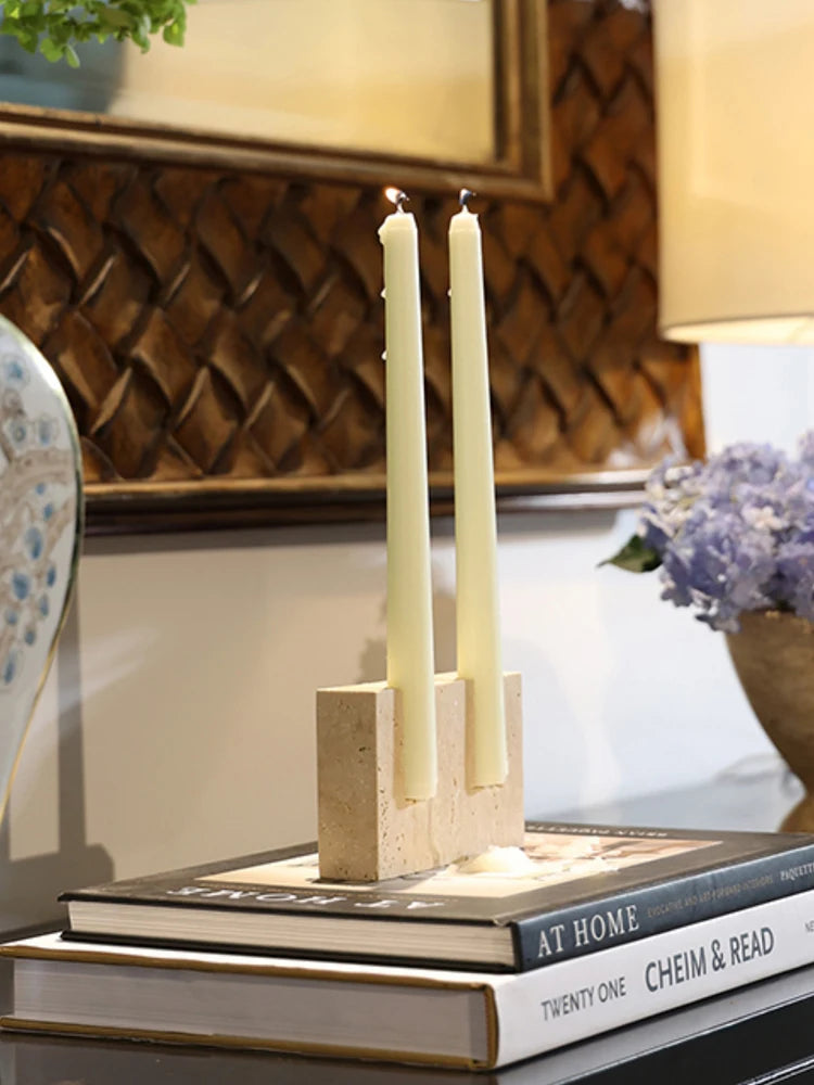 Travertine two-hole candle holder with cream taper candles on a stack of books