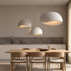 Three white pendant lights over a dining table (sold individually)