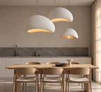 Three white pendant lights in different sizes over a dining table (sold individually)